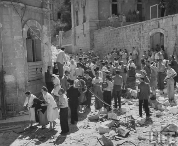 A crowd of Jewish residents gathered amid rubble during the fall of the Jewish Quarter of Jerusalem in 1948.